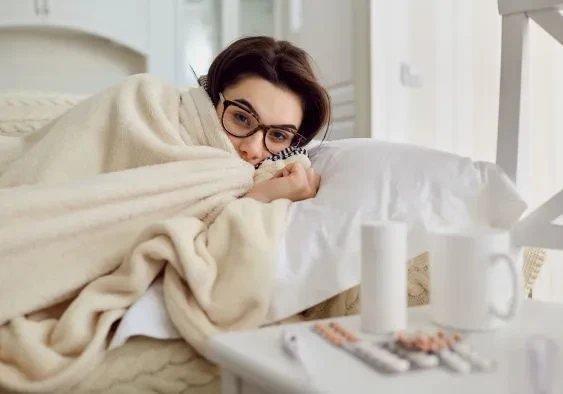 Woman experiencing a sick day snuggling inside a blanket