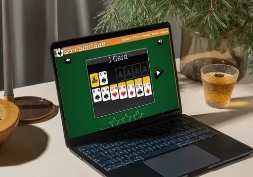 An open laptop screen showing a game of solitaire from 247 Solitaire